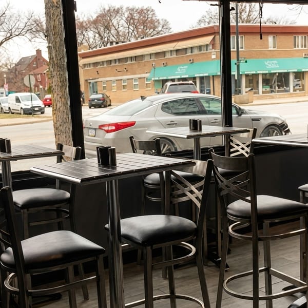 Interior view of a restaurant with high-top tables and chairs looking out onto a street.