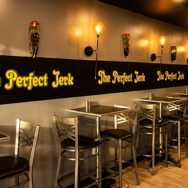 Interior of The Perfect Jerk restaurant with high-top tables, bar stools, and wall decor.